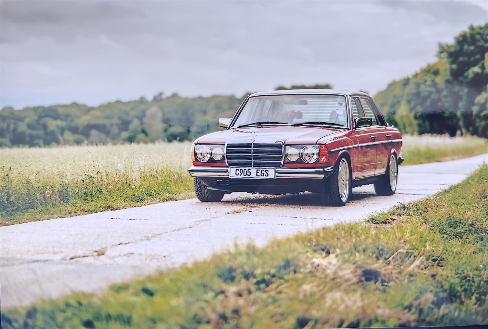 Red Mercedes-Benz W123 on a quiet country road at dusk