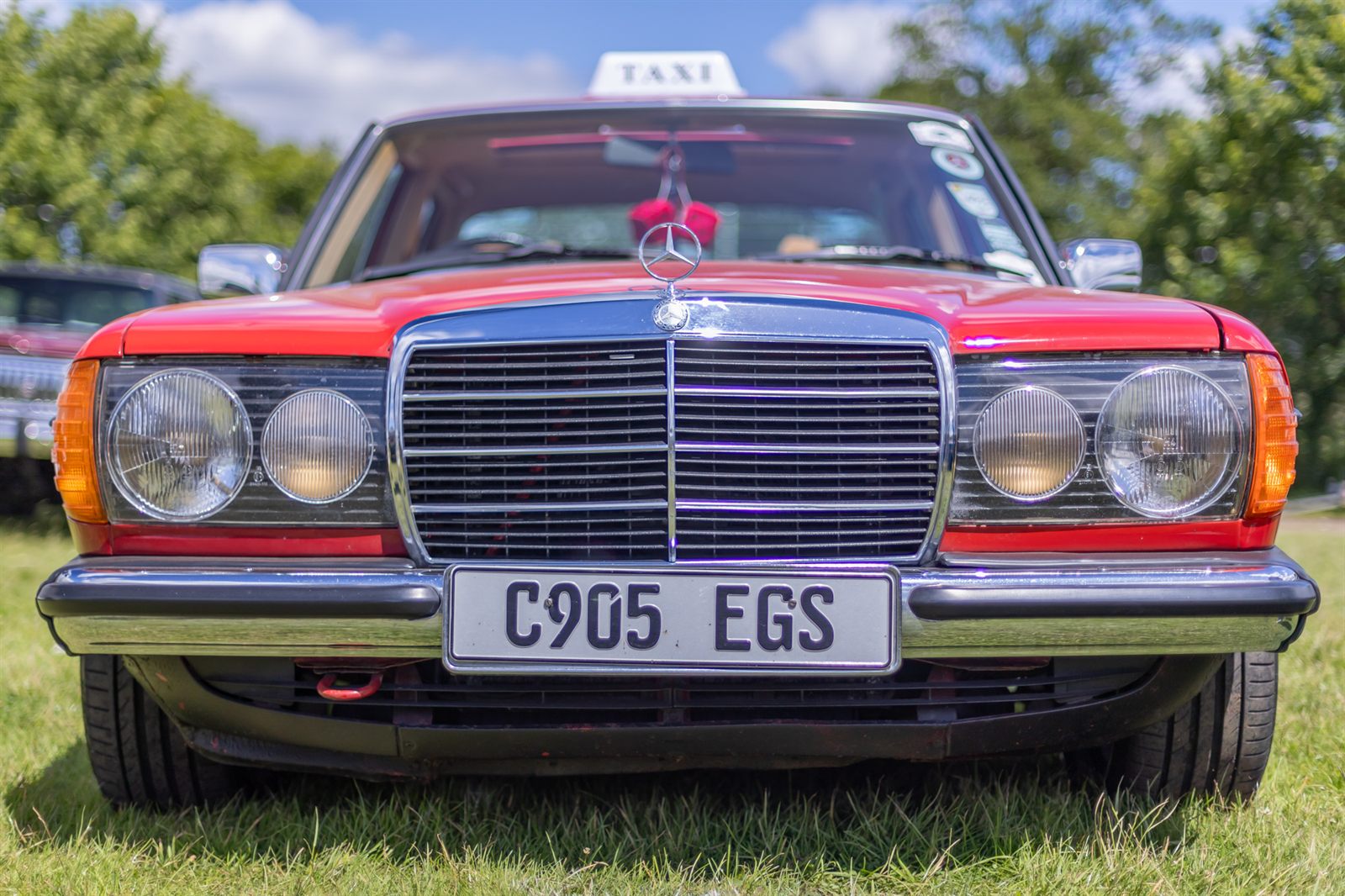 Front view of the red 1985 Mercedes W123, registration C905 EGS, with the star on the bonnet